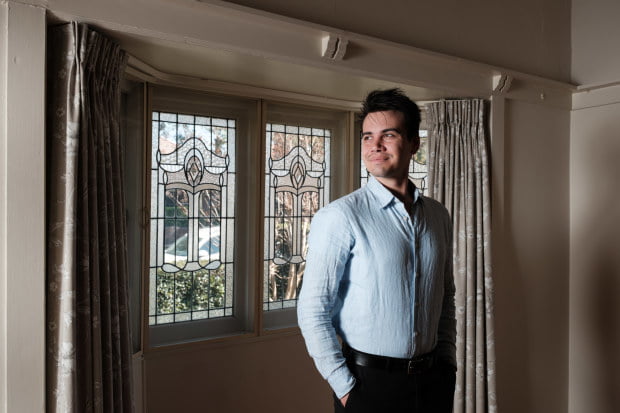 A man standing in front of a window in a room.